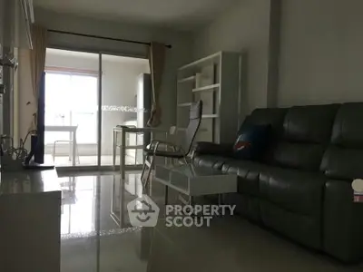 Modern living room with sleek furniture and sliding glass doors leading to a bright dining area.