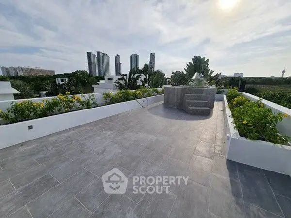 Spacious rooftop terrace with city skyline views and lush greenery.