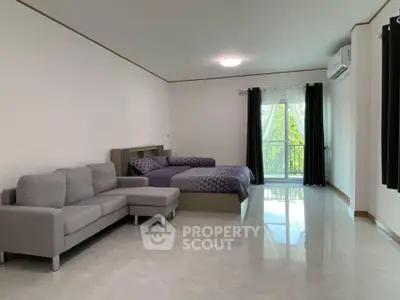 Spacious studio apartment with modern furnishings and a balcony view.