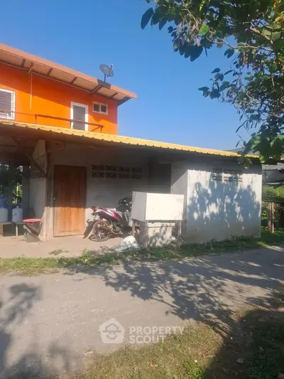 Charming two-story home with vibrant orange facade and lush greenery, perfect for serene living.