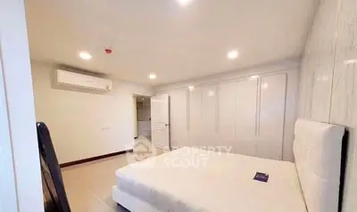 Spacious bedroom with modern white furniture and ample closet space.