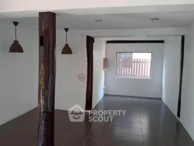 Spacious open-plan room with rustic wooden beams and modern lighting