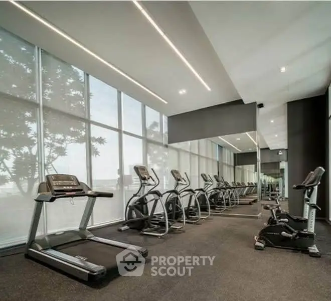 Modern gym with state-of-the-art equipment and large windows offering natural light.