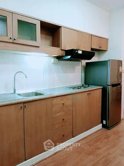 Modern kitchen with wooden cabinets and stainless steel appliances in a cozy apartment.