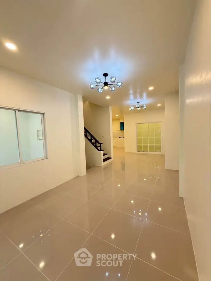 Spacious open-plan living area with modern lighting and glossy tile flooring.