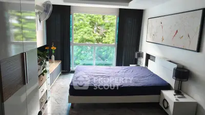 Spacious bedroom with large window and modern decor overlooking lush greenery.
