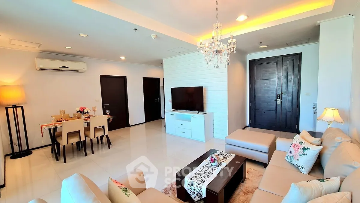 Spacious modern living room with elegant decor and dining area, featuring a chandelier and cozy seating.