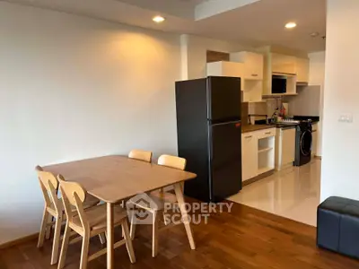 Modern kitchen with dining area featuring wooden table and chairs, sleek appliances, and stylish cabinetry.