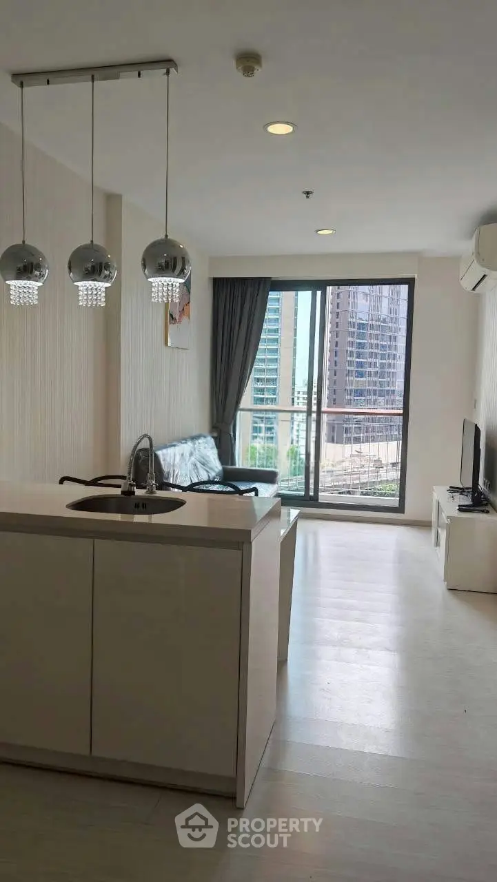 Modern living room with open kitchen and city view balcony in high-rise apartment.