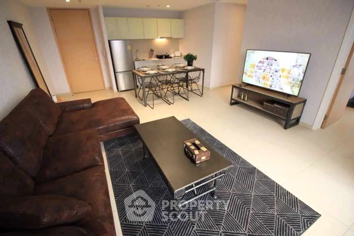 Modern living room with brown sofa, stylish rug, and sleek dining area