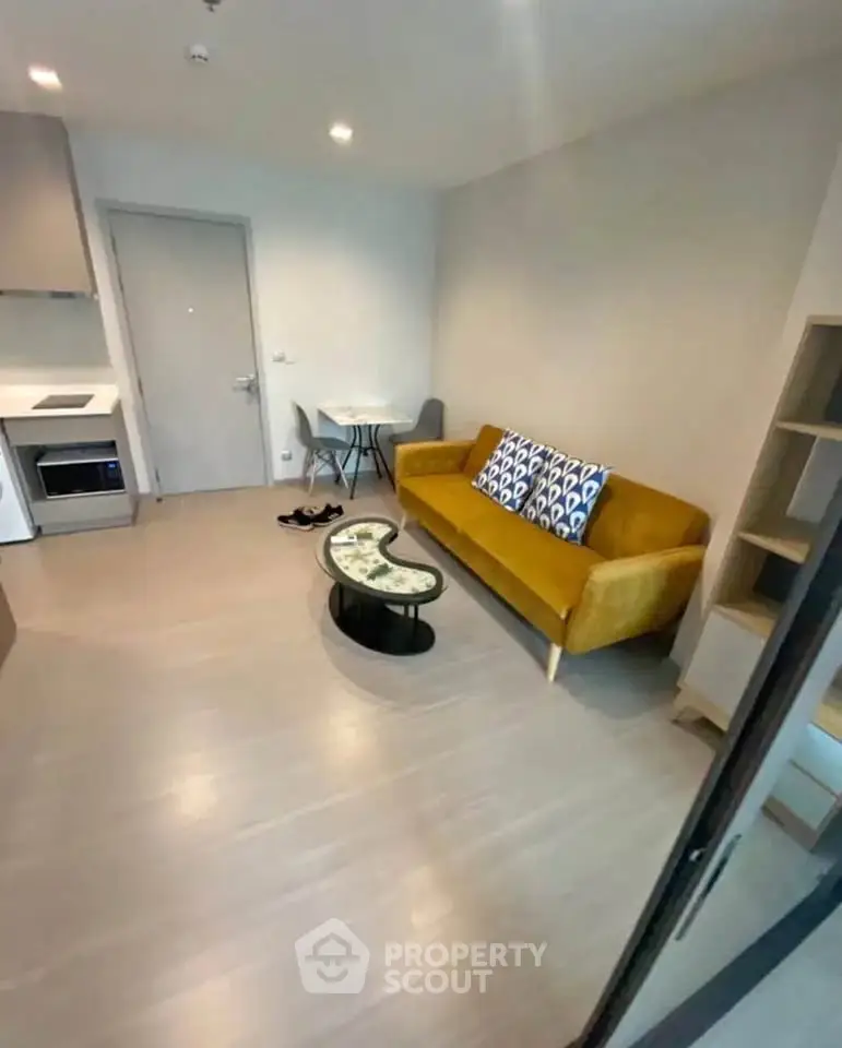 Modern living room with stylish yellow sofa and compact kitchen area