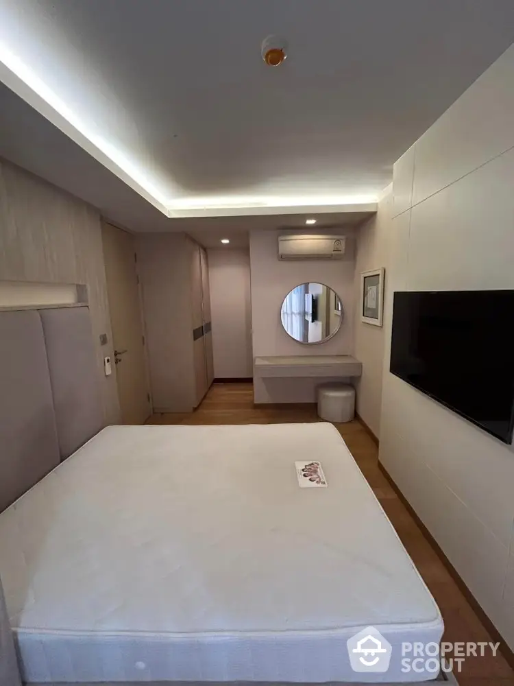 Modern bedroom with sleek design, featuring a wall-mounted TV and stylish vanity area.