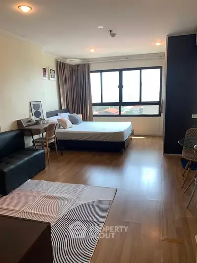 Spacious studio apartment with modern decor and large windows offering a stunning city view.