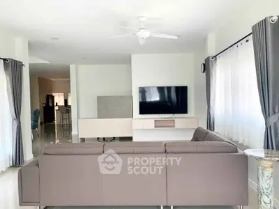 Spacious modern living room with sleek furniture and large TV, perfect for relaxation.