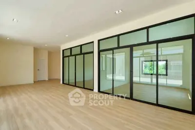 Spacious modern living room with large glass doors and wooden flooring.