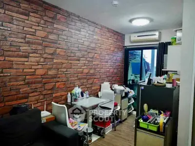 Cozy living room with brick accent wall and modern furnishings in a compact apartment.