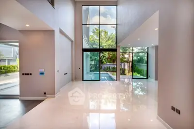 Luxurious modern living room with high ceilings and large windows overlooking a private pool.