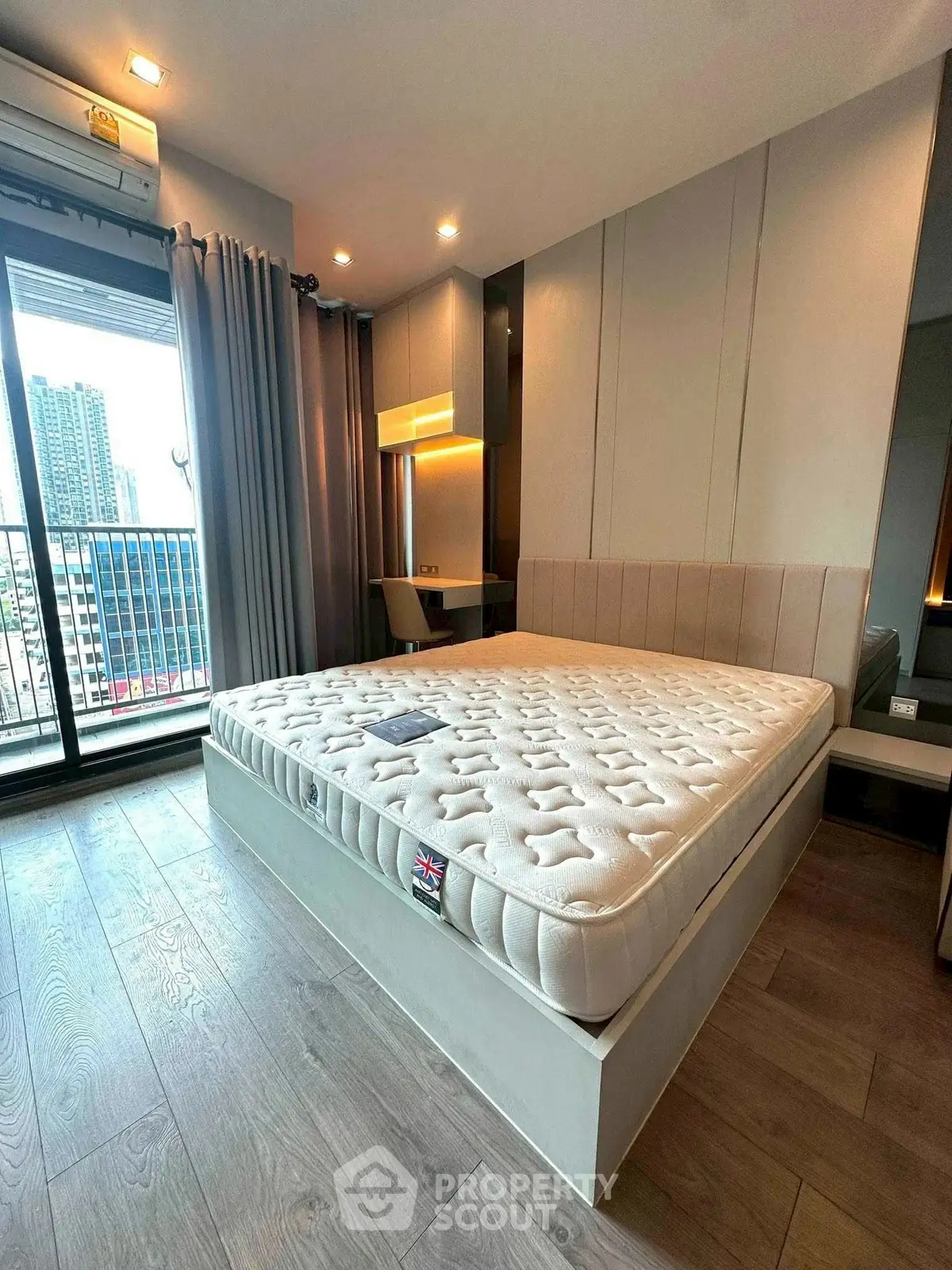 Modern bedroom with large window and city view, featuring a comfortable bed and stylish decor.