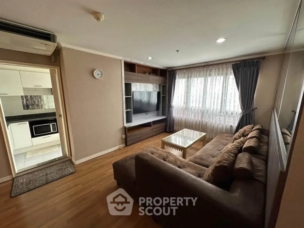Spacious living room with cozy sofa and entertainment center, adjacent to modern kitchen.