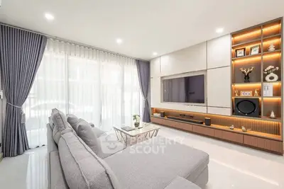 Modern living room with elegant gray sofa, built-in shelving, and large TV, perfect for relaxation and entertainment.