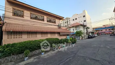 Charming residential street view with lush greenery and multi-story buildings.