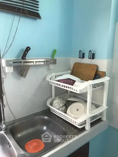 Compact kitchen corner with dish rack and knife holder, maximizing space efficiency.