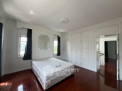 Spacious bedroom with hardwood floors and built-in wardrobes in a bright, airy setting.