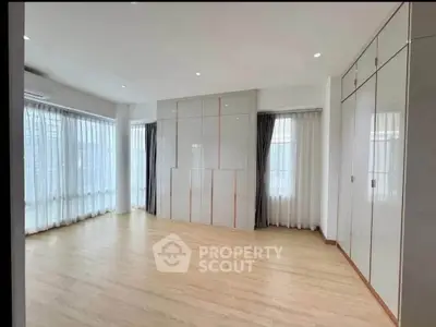 Spacious empty room with large windows and wooden flooring, perfect for customization.