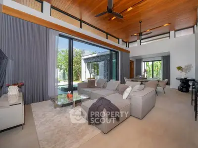 Luxurious modern living room with high ceilings and large windows opening to a garden view.