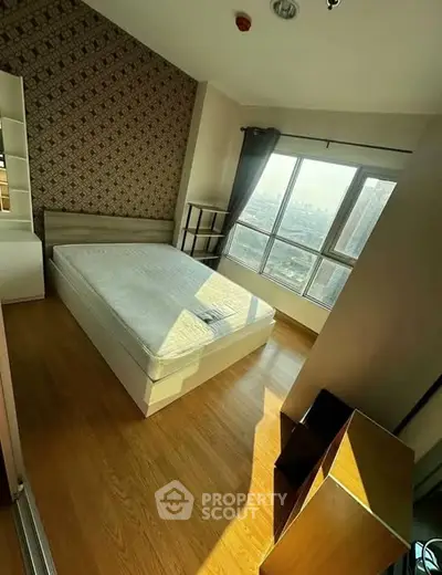 Spacious bedroom with large windows and city view, featuring modern decor and wooden flooring.