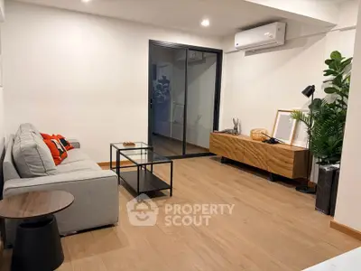 Modern living room with sleek furniture and wooden flooring, featuring a cozy sofa and stylish decor.