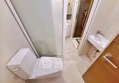 Modern bathroom with sleek fixtures and glass shower enclosure in a contemporary apartment.