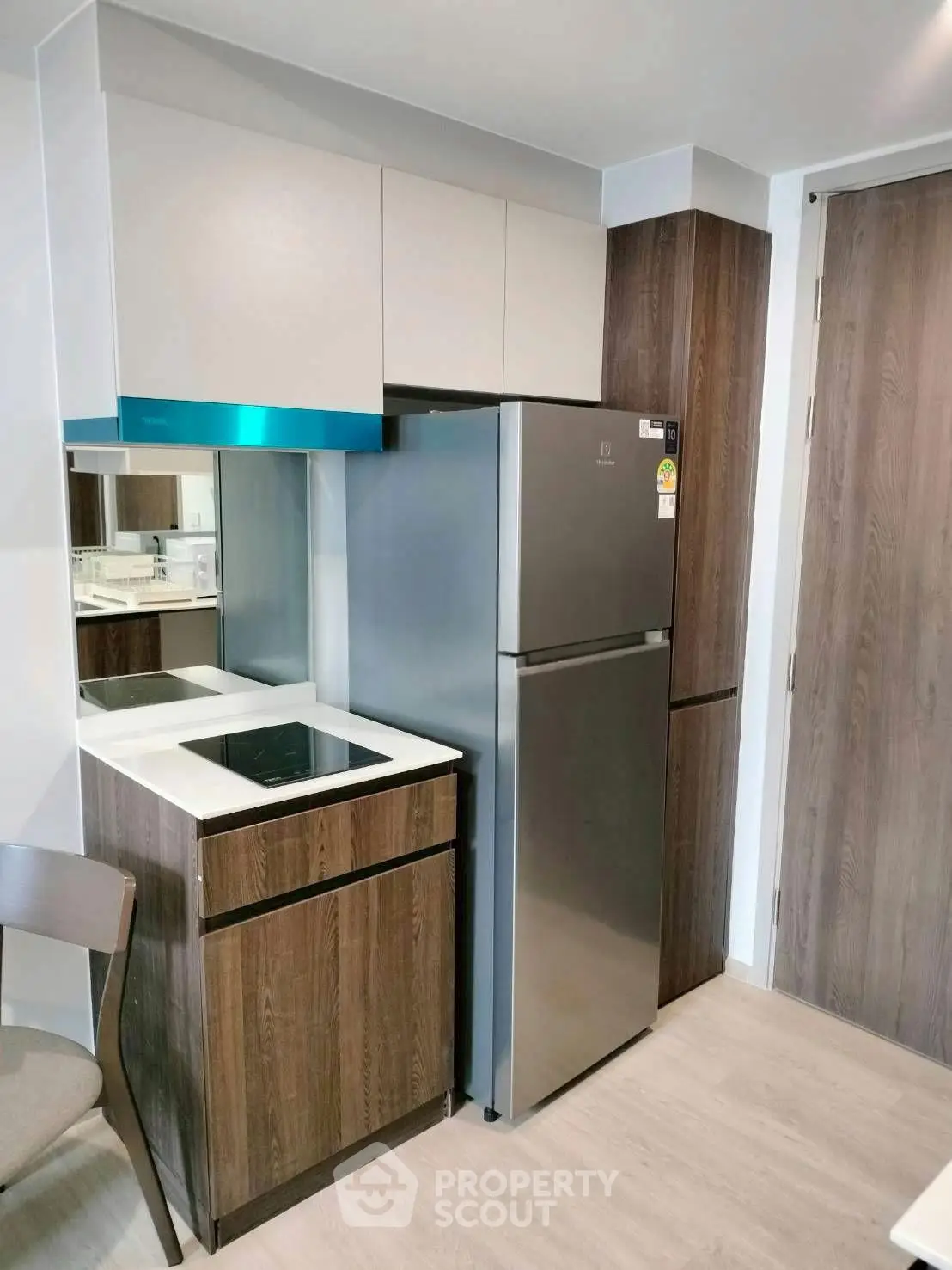 Modern compact kitchen with sleek appliances and stylish cabinetry in a contemporary apartment.