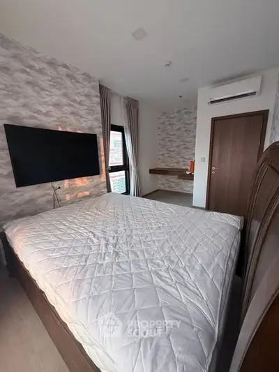 Modern bedroom with stylish decor and wall-mounted TV, featuring a cozy atmosphere.