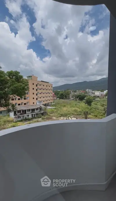 Scenic balcony view overlooking lush greenery and distant mountains, perfect for relaxation.