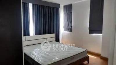 Modern bedroom with large windows and stylish curtains, featuring a comfortable bed and sleek design.
