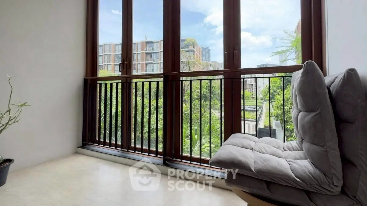 Modern balcony with comfortable seating and scenic view of lush greenery and urban landscape.