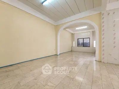 Spacious empty room with tiled flooring and arched doorway, ideal for customization.