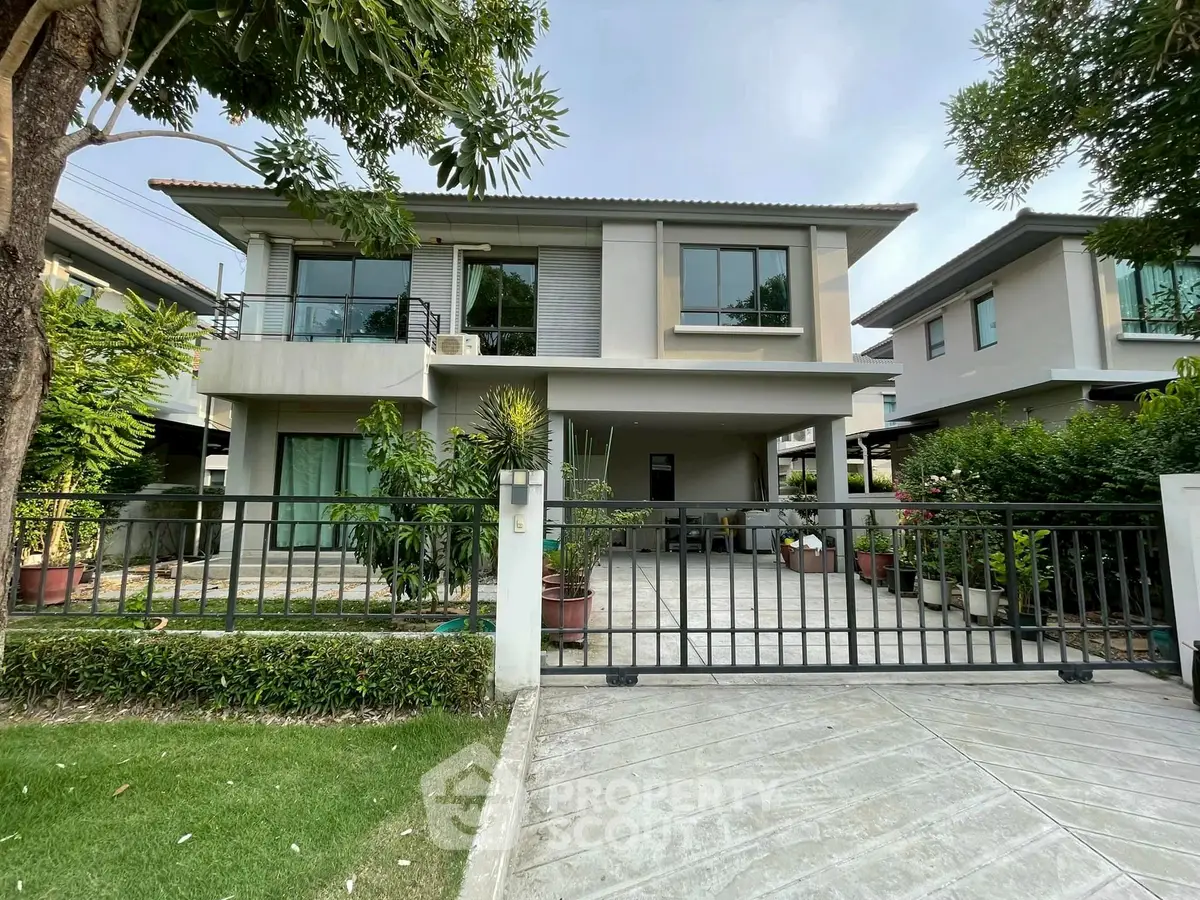 Modern two-story house with lush garden and gated driveway