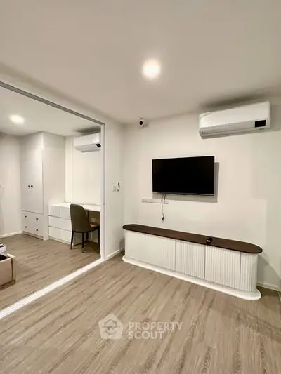 Modern living room with sleek design and wall-mounted TV, featuring stylish wooden flooring.