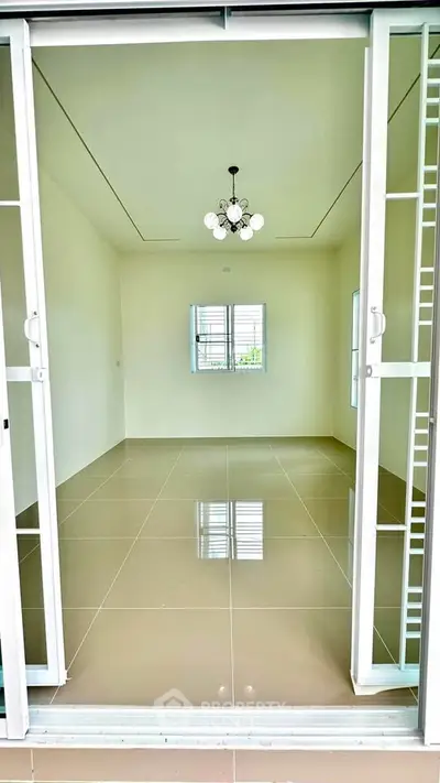 Spacious empty room with glossy tiled floor and modern chandelier, perfect for customization.