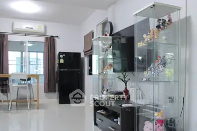 Modern living room with glass display cabinets and sleek furniture in a bright, airy apartment.