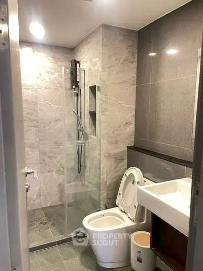Modern bathroom with sleek gray tiles and glass shower enclosure