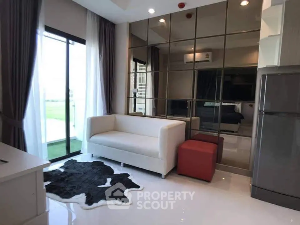 Modern living room with sleek design, mirrored wall, and cozy seating area.