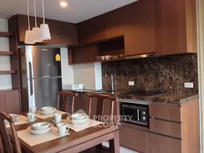 Modern kitchen with wooden cabinets, dining table, and built-in appliances in a cozy apartment.