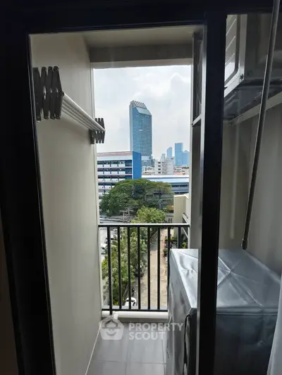 Modern apartment balcony with city view and laundry area, featuring a washing machine and drying rack.