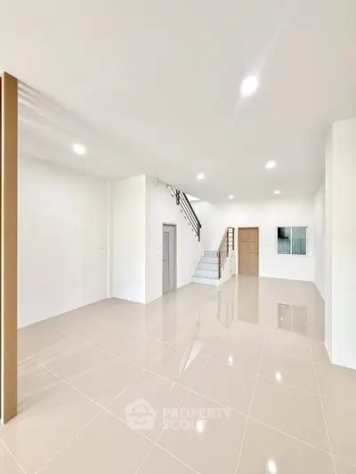 Spacious modern living room with glossy tiled floors and staircase, perfect for family gatherings.