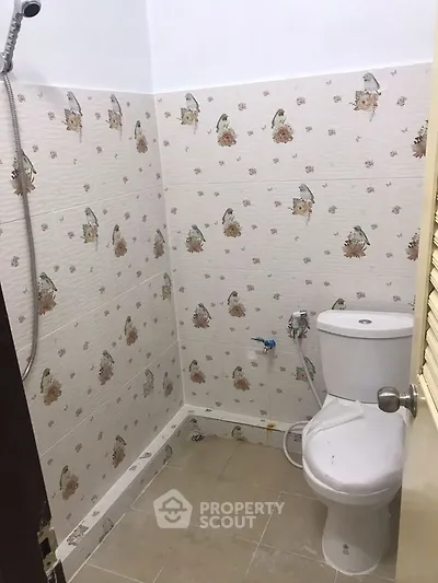 Compact bathroom with floral tiles and standard fixtures