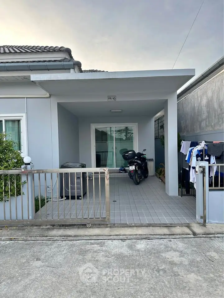 Charming modern home entrance with covered patio and motorbike parking.