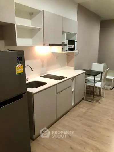 Modern kitchen with sleek cabinetry and dining area in contemporary apartment